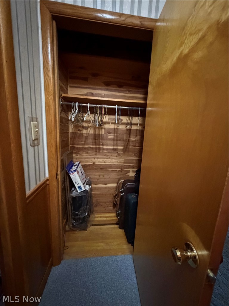 6063 East State Road Newcomerstown, OH 43832 - Photo 13 of 31 Wood-paneled closet with a metal hanging rod, wood-finish flooring, and a natural wood door