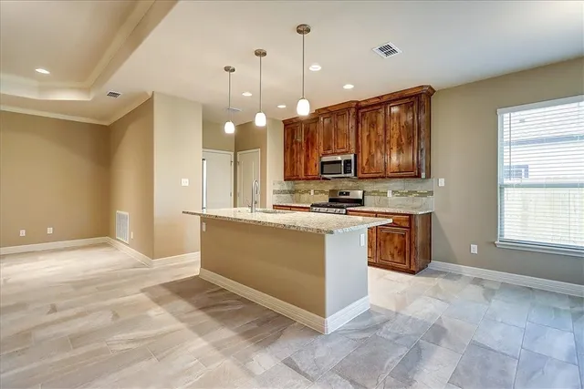 a view of kitchen with stainless steel appliances granite countertop a stove a sink and a microwave