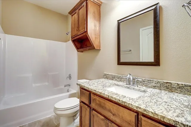 a bathroom with a granite countertop sink a toilet and bathtub