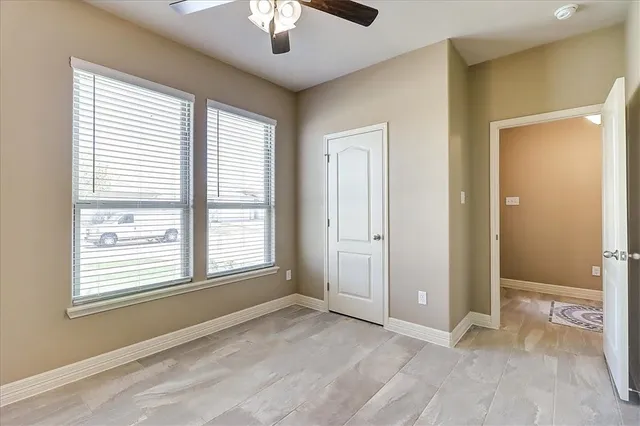 a view of an empty room with chandelier fan and fire place