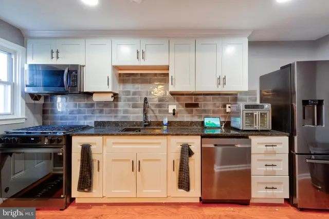 a kitchen with stainless steel appliances granite countertop a stove top oven a sink dishwasher and a refrigerator with wooden cabinets