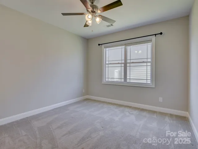 a view of an empty room with a chandelier fan