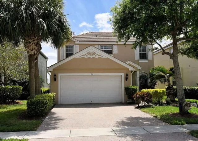 a front view of a house with a garden and trees