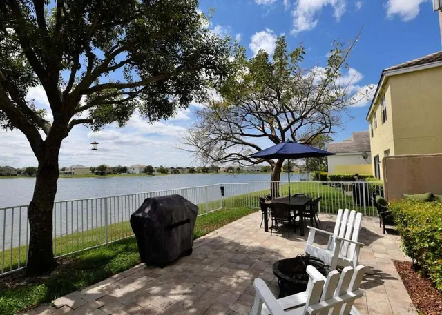 a view of a patio with table and chairs potted plants and a large tree