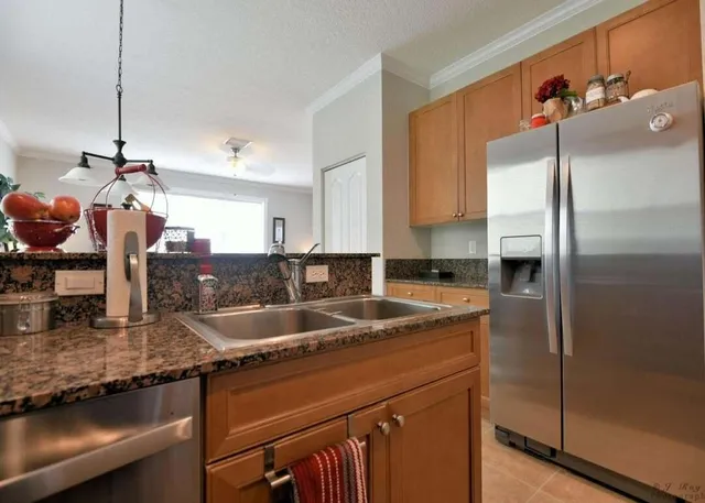 a kitchen with stainless steel appliances granite countertop a sink a refrigerator and a counter space