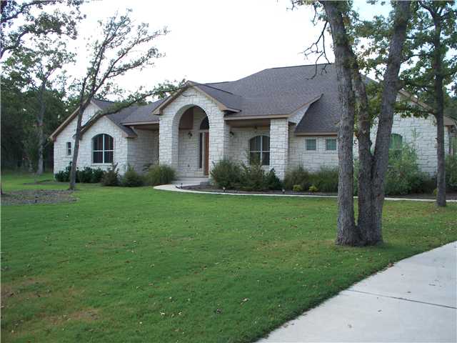 a front view of a house with garden and trees