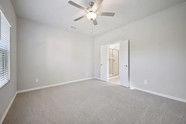 an empty room with a ceiling fan and a window