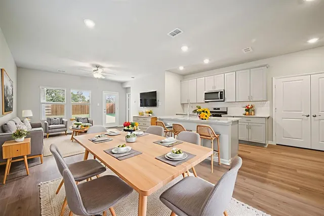 a open dining room with stainless steel appliances kitchen island granite countertop a dining table chairs and a refrigerator