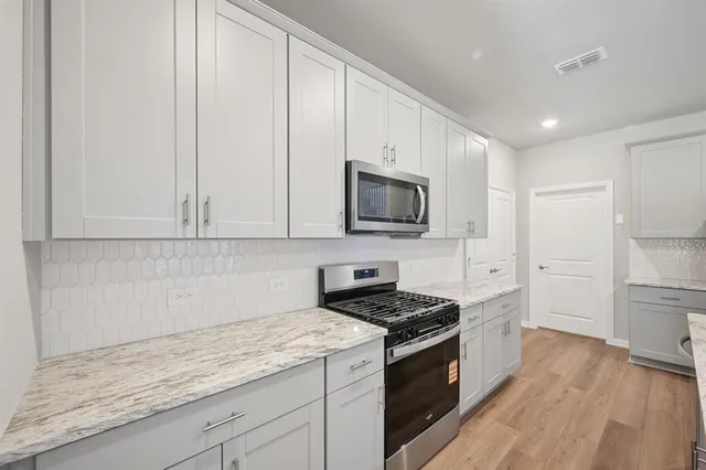 a kitchen with granite countertop white cabinets and stainless steel appliances