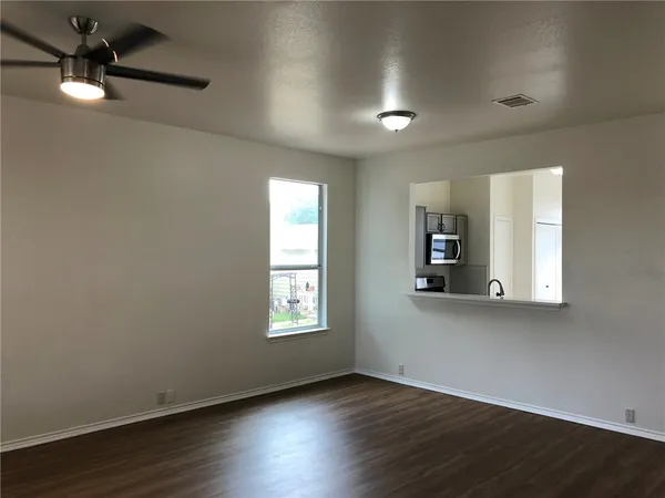 an empty room with wooden floor a ceiling fan and windows