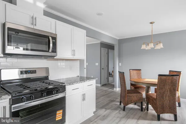 a kitchen with stainless steel appliances a stove a microwave a dining table and chairs