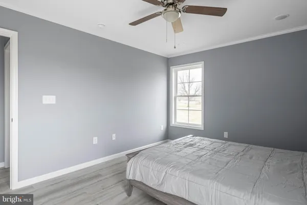a bedroom with wooden floor and ceiling fan