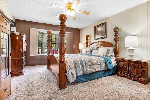 a bedroom with a large bed and a chandelier fan