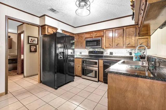 a kitchen with stainless steel appliances granite countertop a refrigerator a stove and a sink