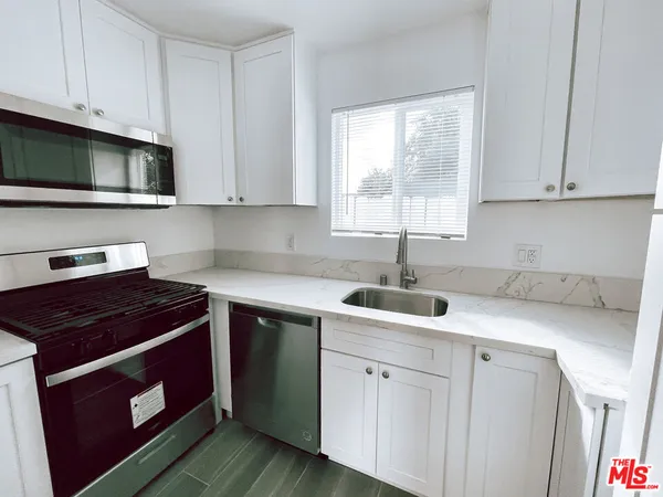 a kitchen with white cabinets sink and window