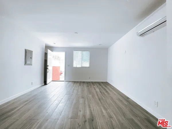 a view of an empty room with wooden floor and a window