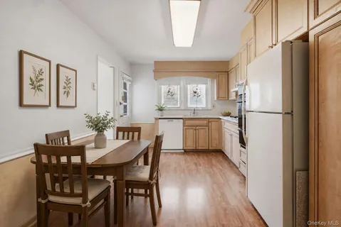 a white kitchen with a table chairs refrigerator and cabinets