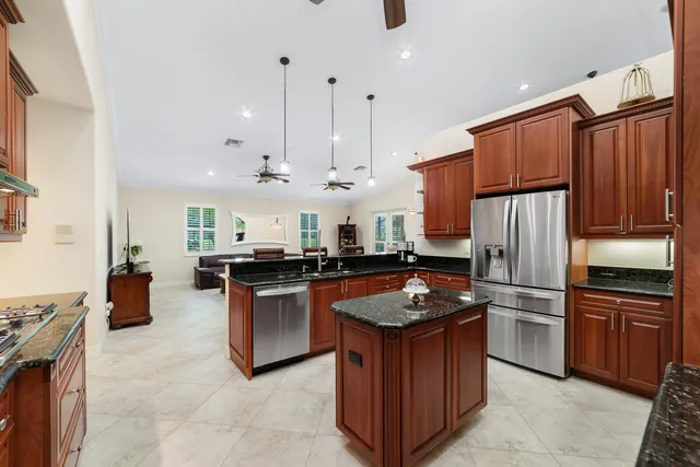a kitchen with stainless steel appliances kitchen island granite countertop a stove a refrigerator a oven a sink with a dining table and chairs