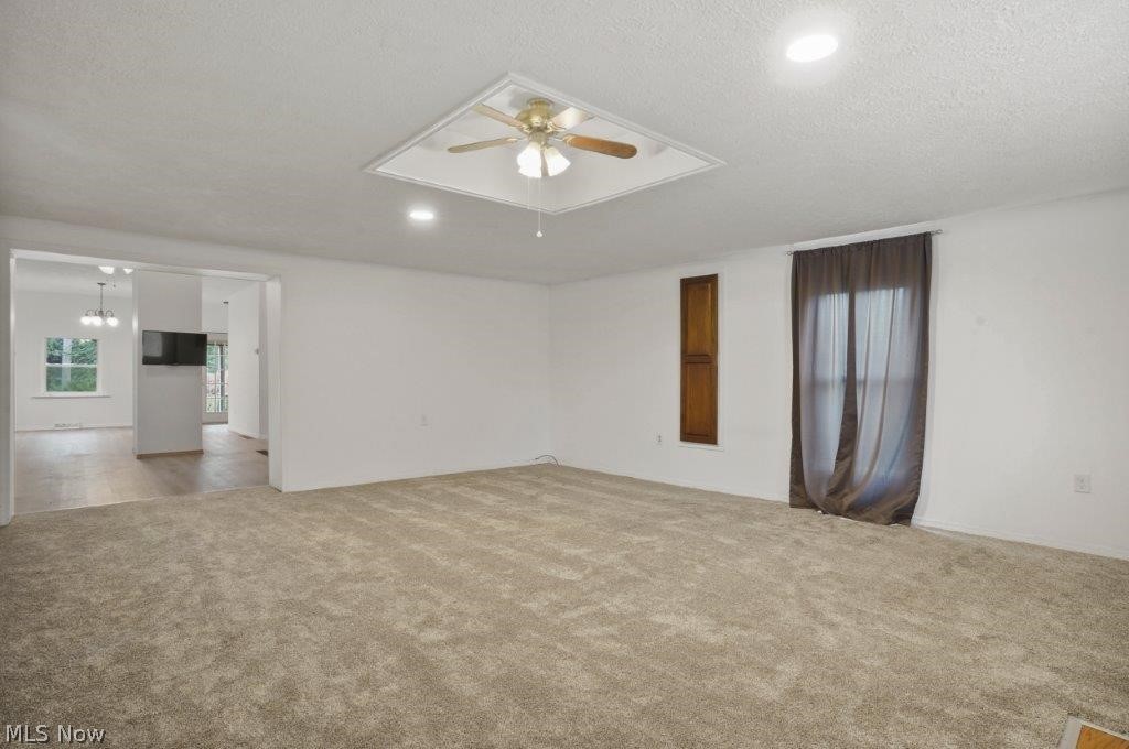 4325 Mayfair Road Uniontown, OH 44685 - Photo 13 of 35 Carpeted spare room featuring ceiling fan with notable chandelier and a textured ceiling