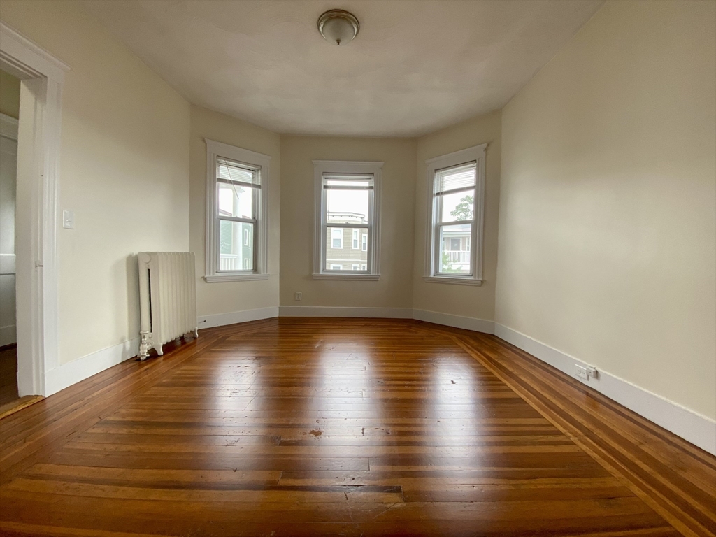 14 Belknap Street, Unit 3 Somerville, MA 02144 - Photo 11 of 25 an empty room with wooden floor and windows