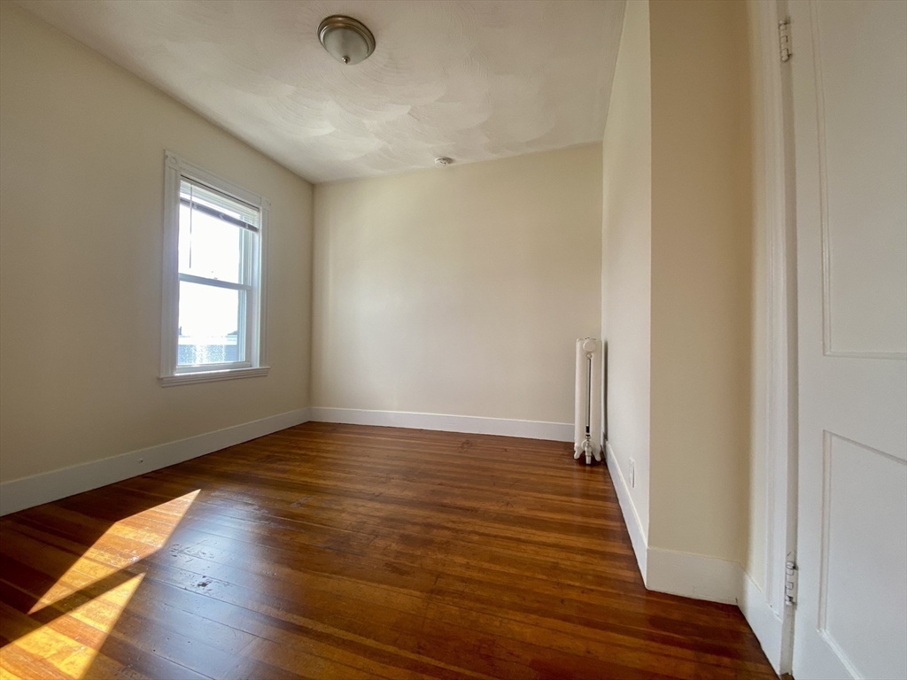 14 Belknap Street, Unit 3 Somerville, MA 02144 - Photo 18 of 25 a view of an empty room with wooden floor and a window