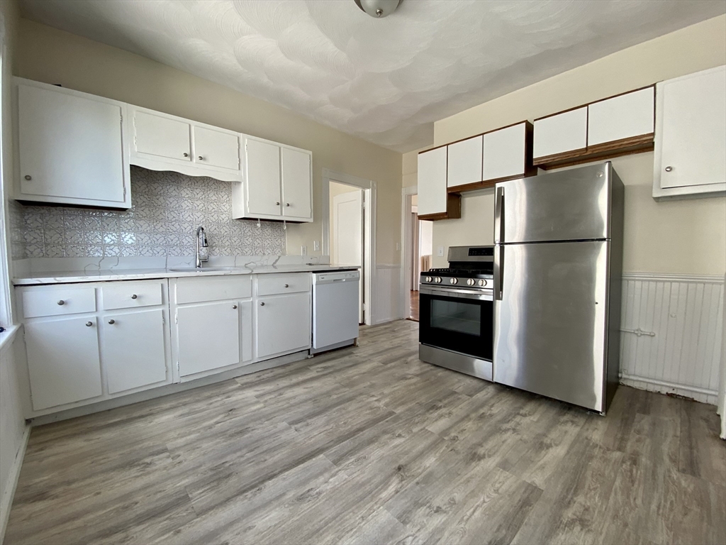 14 Belknap Street, Unit 3 Somerville, MA 02144 - Photo 3 of 25 a kitchen with granite countertop white cabinets and stainless steel appliances