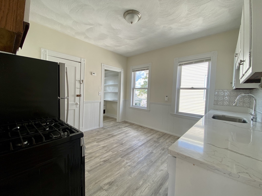 14 Belknap Street, Unit 3 Somerville, MA 02144 - Photo 6 of 25 a kitchen with granite countertop a stove and a refrigerator