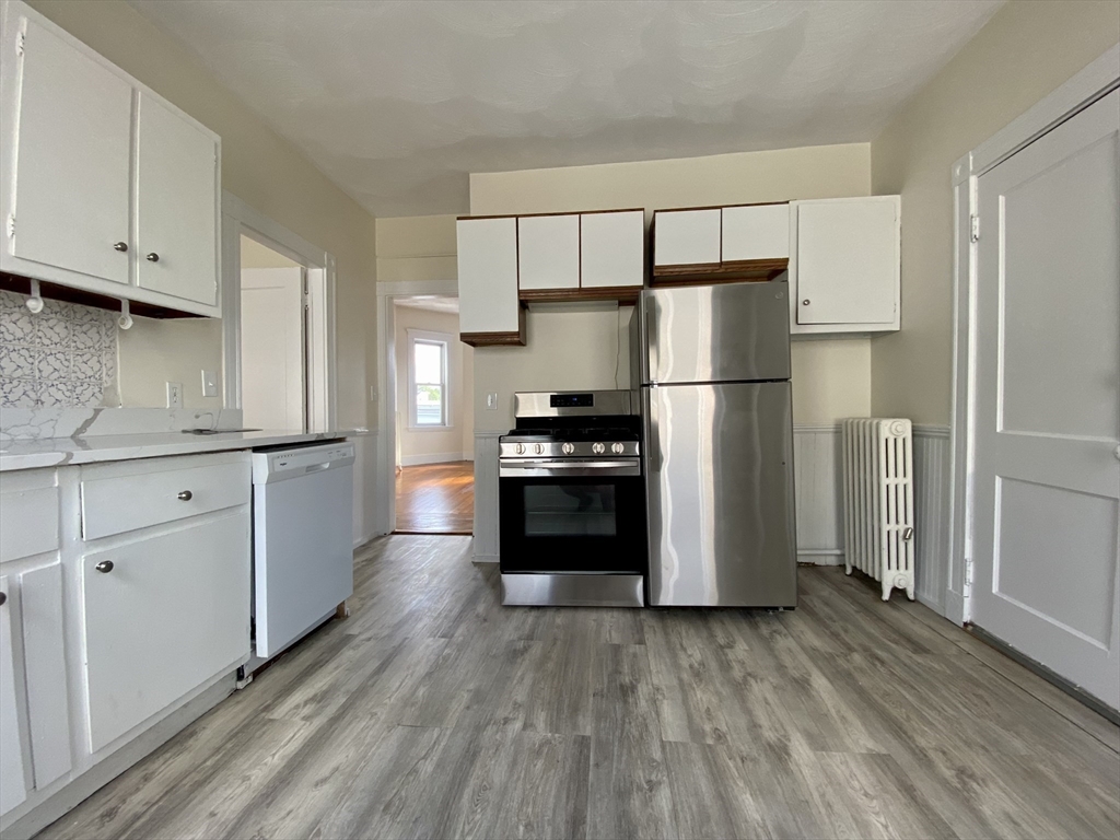 14 Belknap Street, Unit 3 Somerville, MA 02144 - Photo 7 of 25 a kitchen with a refrigerator a stove top oven and wooden floors