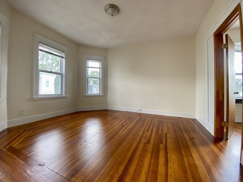 14 Belknap Street, Unit 3 Somerville, MA 02144 - Photo 10 of 25 an empty room with wooden floor and windows