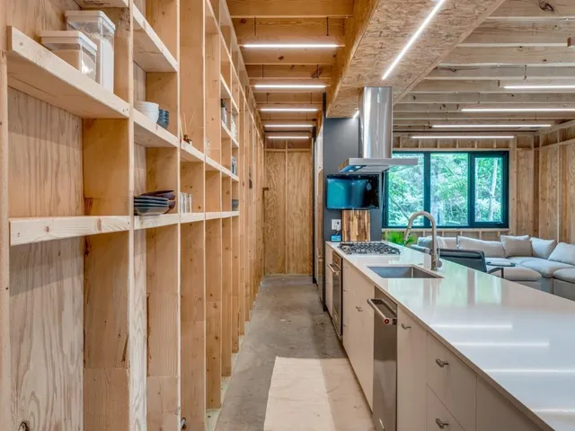 a large kitchen with kitchen island a large window a sink and stainless steel appliances