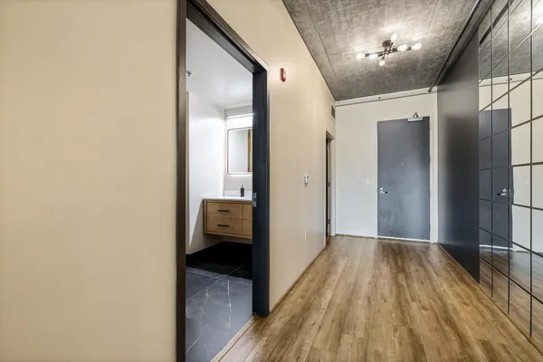 a view of a hallway with wooden floor and a bathroom