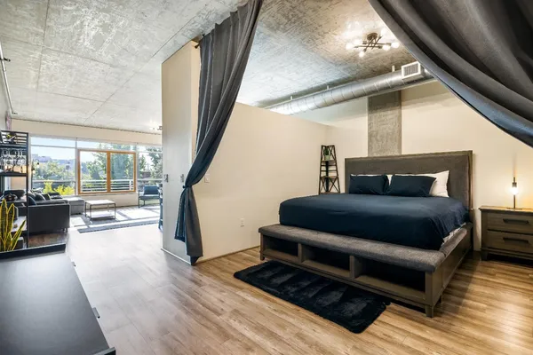 a bedroom with a bed wooden floor and a large window
