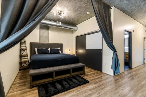 a bedroom with wooden floor and stairs