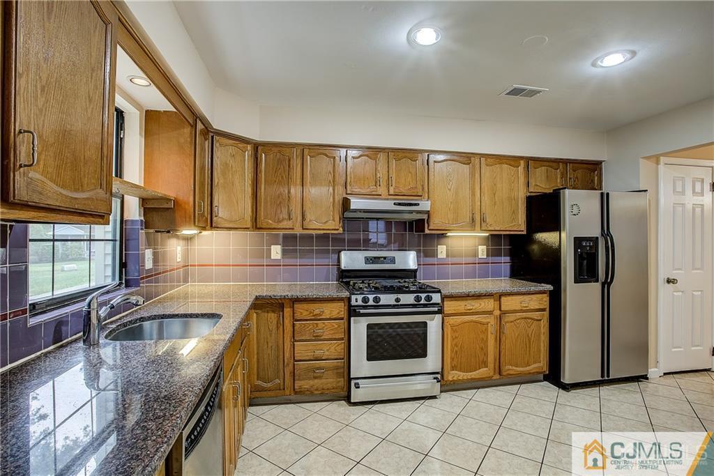 901 Timber Oaks Road Edison, NJ 08820 - Photo 12 of 27 a kitchen with stainless steel appliances granite countertop a stove a sink and a microwave