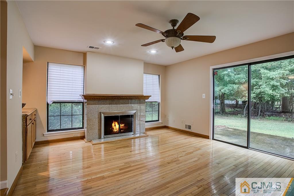 901 Timber Oaks Road Edison, NJ 08820 - Photo 7 of 27 an empty room with wooden floor fireplace and windows