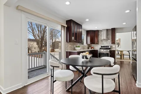 a kitchen with stainless steel appliances kitchen island granite countertop a dining table chairs and a refrigerator