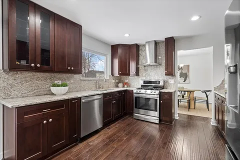 a kitchen with stainless steel appliances granite countertop wooden cabinets a stove top oven a sink and dishwasher