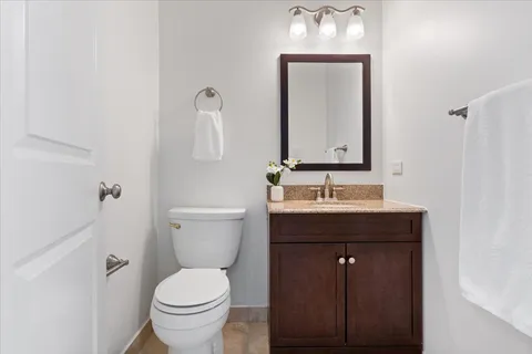 a bathroom with a granite countertop sink a toilet and mirror