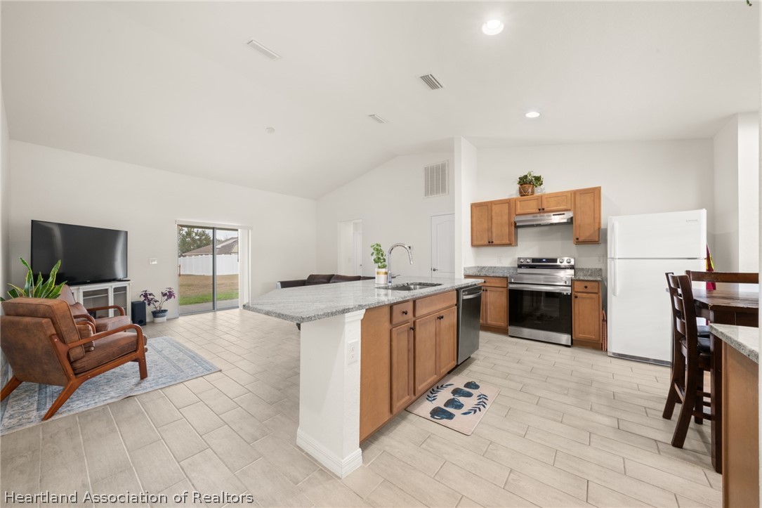1204 Ridge Drive Avon Park, FL 33825 - Photo 5 of 20 a open kitchen with stainless steel appliances kitchen island granite countertop a stove top oven a sink dishwasher a dining table and chairs with wooden floor