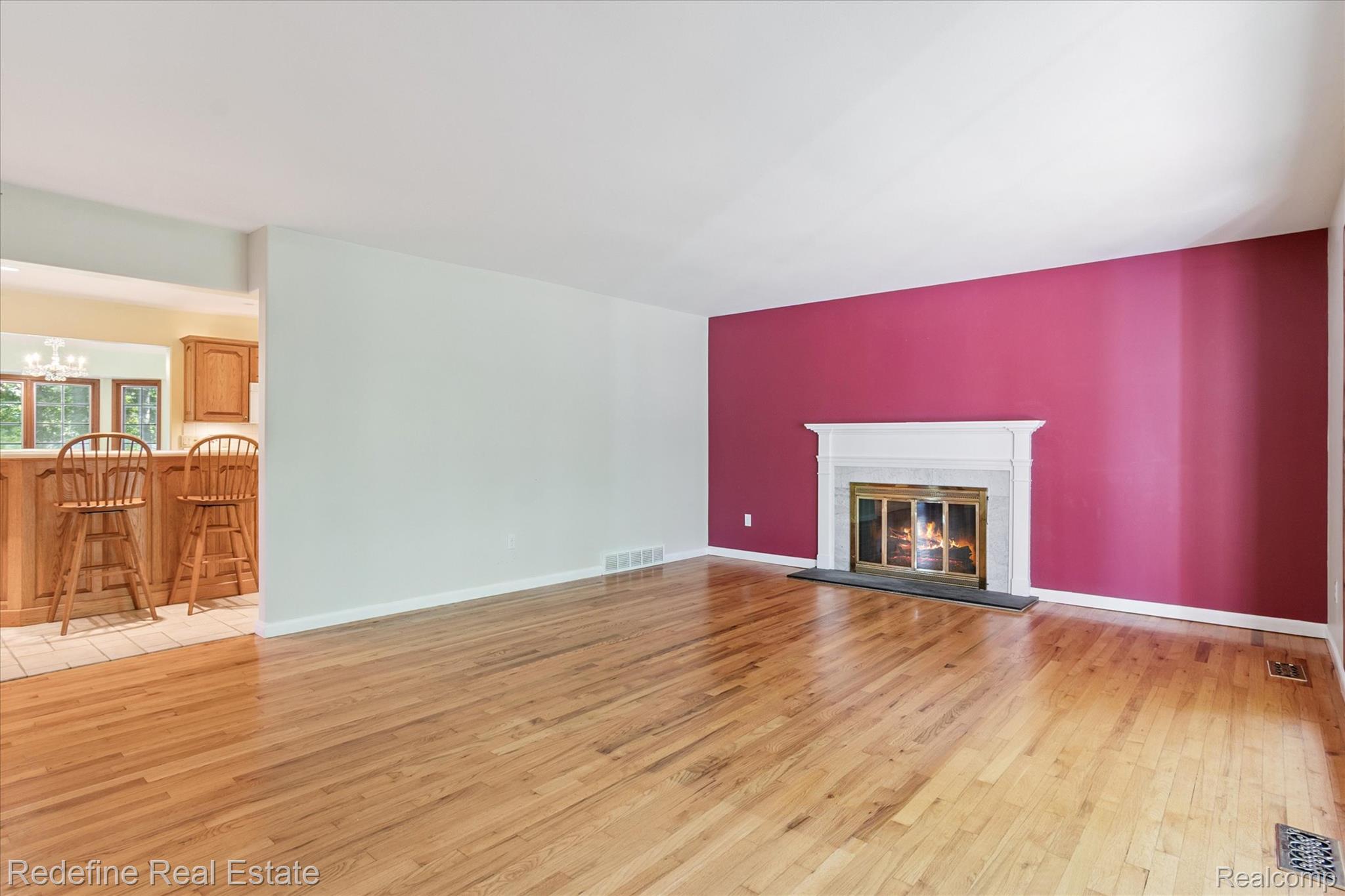 3777 Dorr Road Brighton, MI 48116 - Photo 18 of 77 Unfurnished living room featuring light wood-type flooring, a glass covered fireplace, and a chandelier