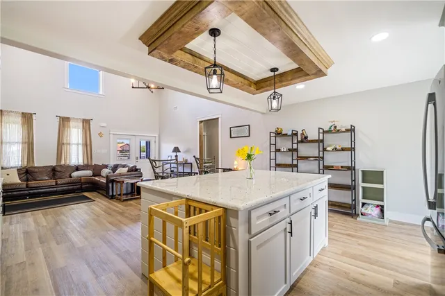 a view of a kitchen with kitchen island a stove a refrigerator wooden floor and a dining table