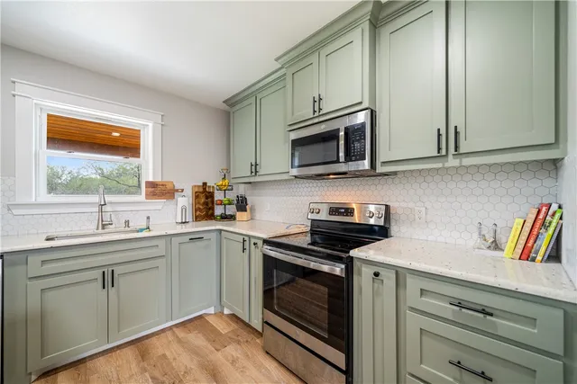 a kitchen with granite countertop a sink stainless steel appliances and cabinets