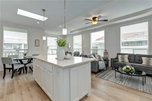 a living room with furniture a dining table wooden floor and a large window