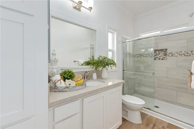 a bathroom with a granite countertop sink a toilet and shower