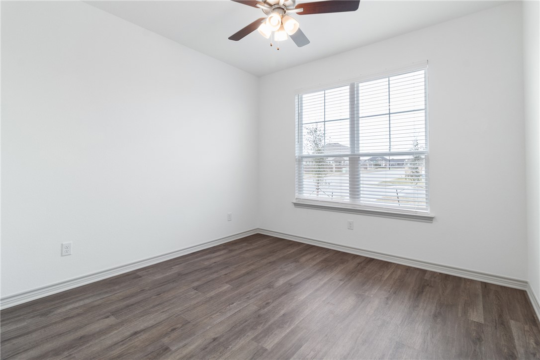 1900 Stubbs Drive Bryan, TX 77807 - Photo 14 of 15 an empty room with wooden floor chandelier fan and windows