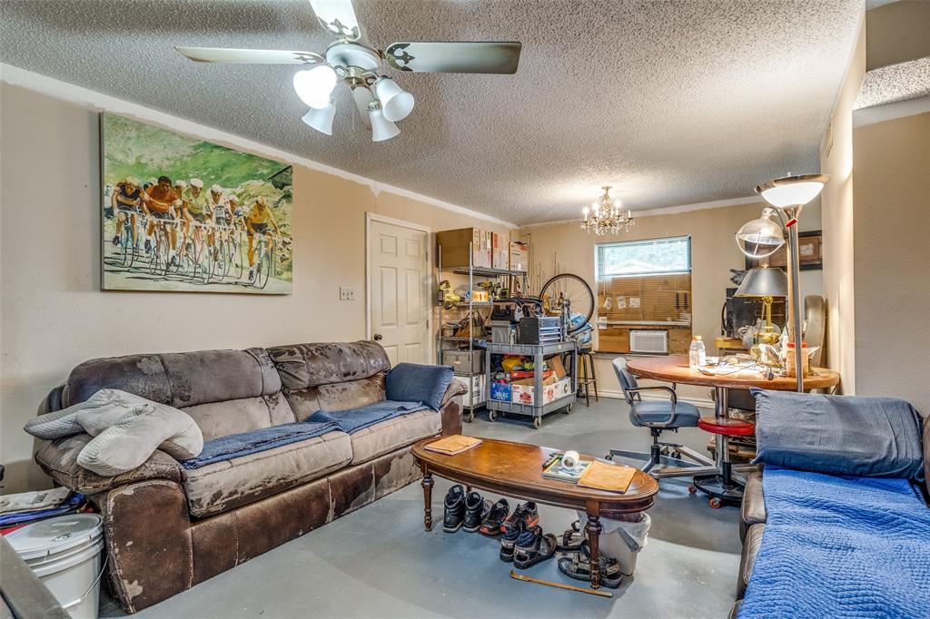 101 Gordon Drive Azle, TX 76020 - Photo 7 of 25 Living room with concrete floors, a textured ceiling, a chandelier, a ceiling fan, and crown molding