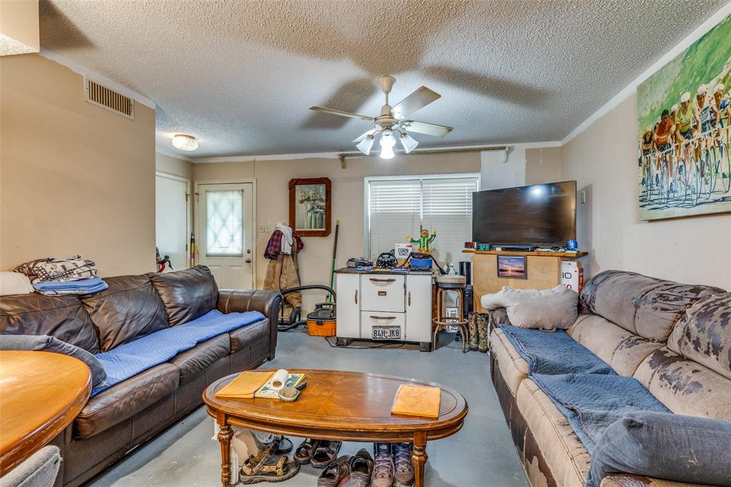 101 Gordon Drive Azle, TX 76020 - Photo 9 of 25 Living room with concrete flooring, a textured ceiling, a ceiling fan, and crown molding
