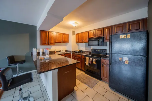 a kitchen with stainless steel appliances granite countertop a refrigerator a stove top oven and a sink with wooden floor