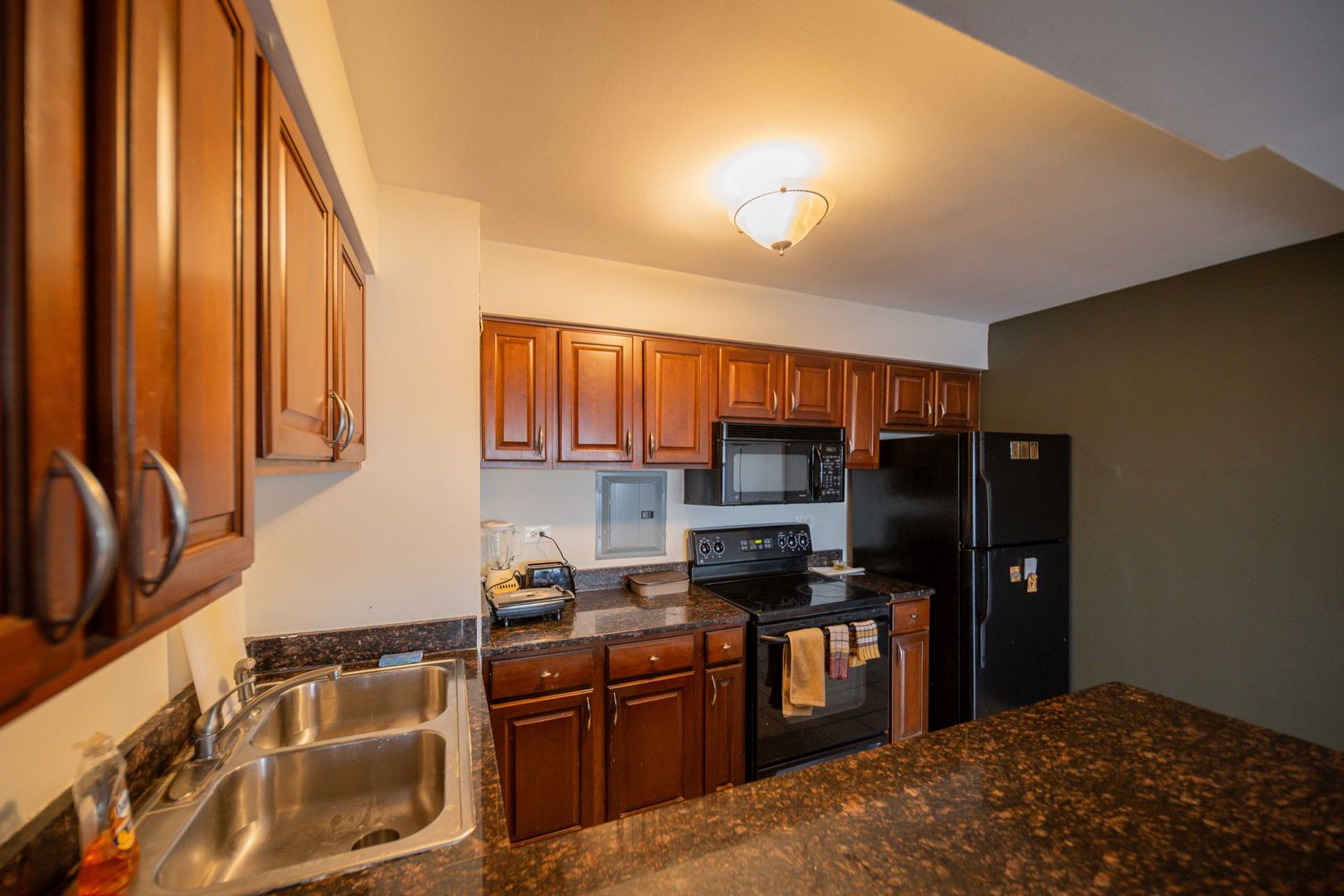 6030 North Sheridan Road, Unit 2011 Chicago, IL 60660 - Photo 8 of 26 a kitchen with stainless steel appliances granite countertop a refrigerator a stove top oven and a sink with wooden floor