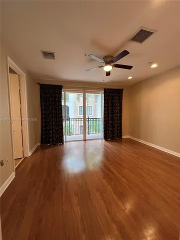 a view of an empty room with a window and wooden floor